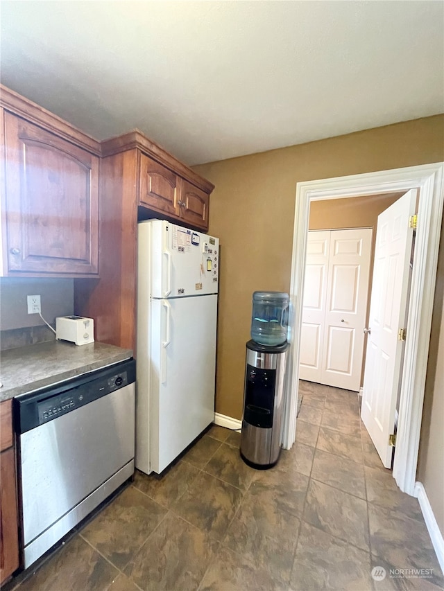 kitchen featuring dark tile flooring, white refrigerator, and stainless steel dishwasher