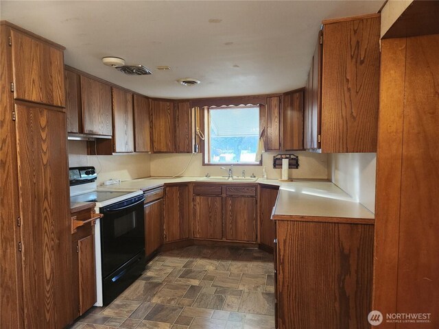 112 Combs Rd, Packwood, WA 98361 - kitchen with electric range, stone finish floor, visible vents, light countertops, and brown cabinets
