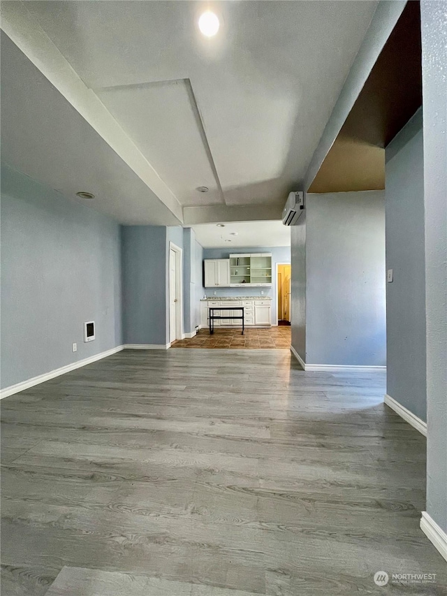 unfurnished living room featuring a wall unit AC and light hardwood / wood-style flooring