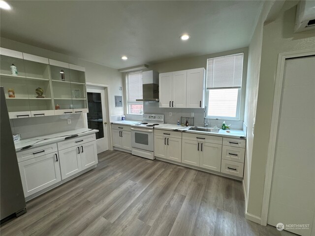 kitchen featuring white range with electric stovetop, white cabinetry, light hardwood / wood-style floors, and sink