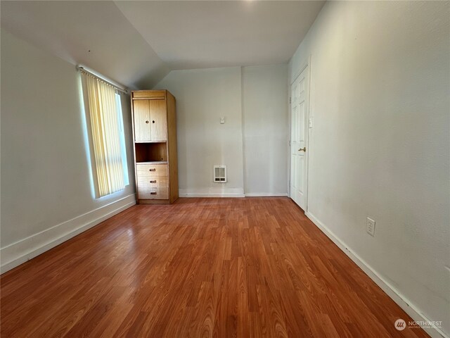 unfurnished bedroom featuring lofted ceiling and wood-type flooring