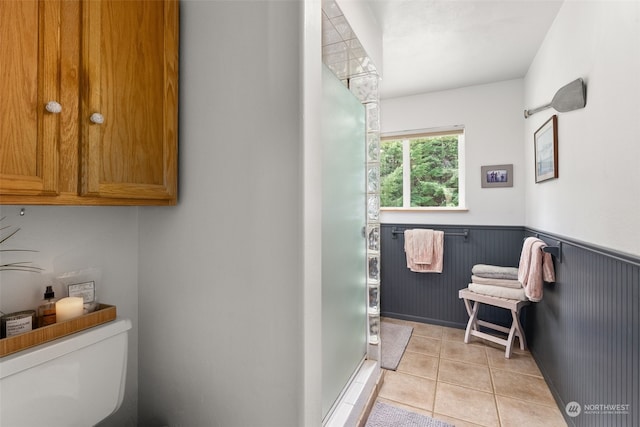 bathroom with toilet, tile patterned floors, and a shower with shower door