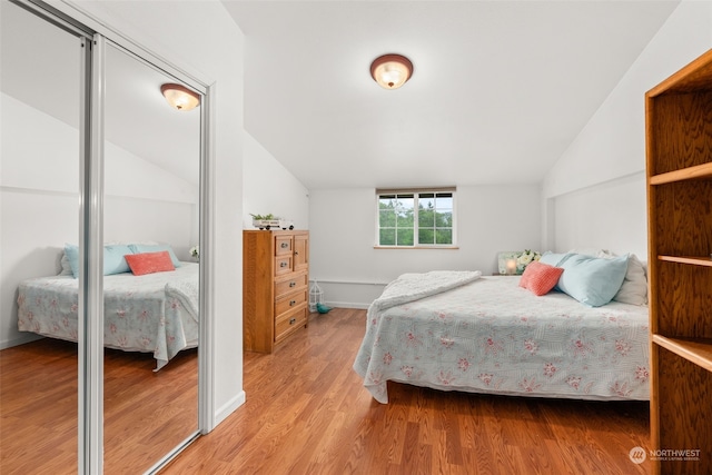 bedroom with light hardwood / wood-style floors and lofted ceiling