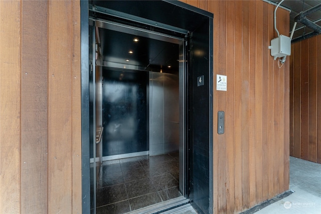 room details with tile flooring, elevator, and wood walls