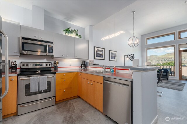 kitchen featuring appliances with stainless steel finishes, sink, kitchen peninsula, and hanging light fixtures