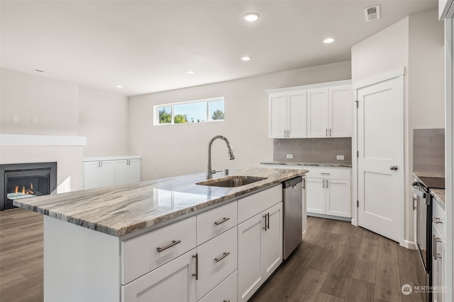 kitchen featuring wood-type flooring, a center island with sink, sink, white cabinetry, and appliances with stainless steel finishes