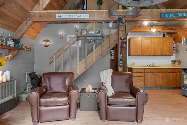 living room featuring lofted ceiling with beams, light hardwood / wood-style flooring, sink, and wooden ceiling