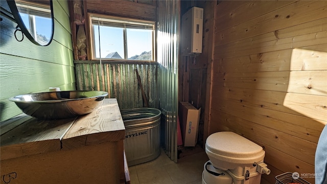 bathroom with wooden walls and tile patterned floors