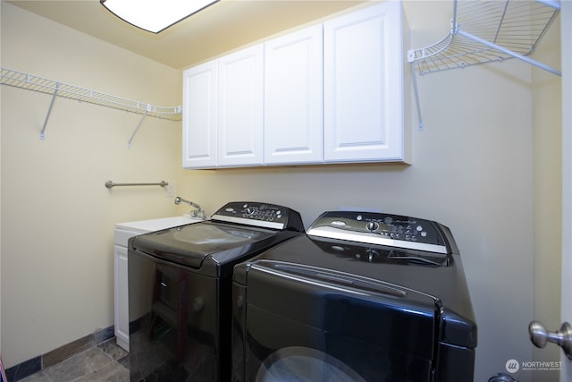 clothes washing area with washing machine and dryer, cabinets, sink, and dark tile floors