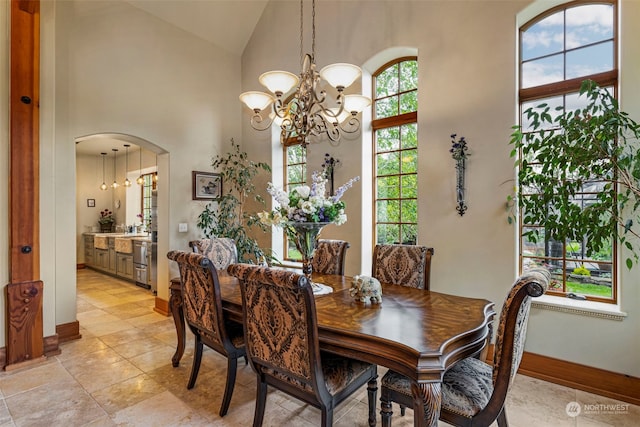 tiled dining area with high vaulted ceiling, a wealth of natural light, and a notable chandelier