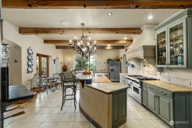 kitchen with decorative light fixtures, an inviting chandelier, backsplash, a kitchen island, and appliances with stainless steel finishes