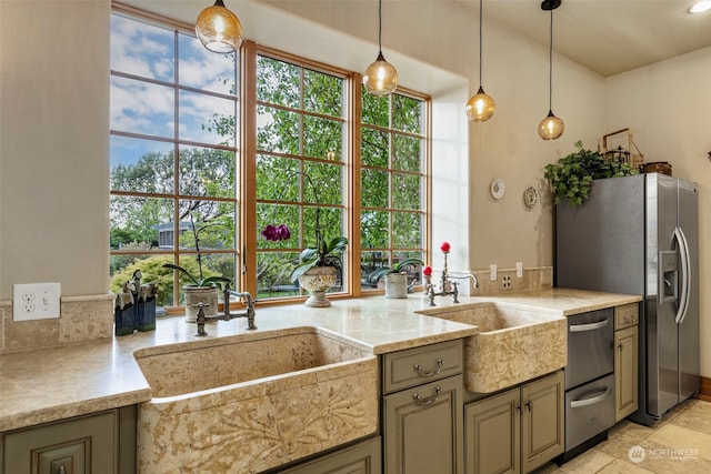 kitchen featuring hanging light fixtures, appliances with stainless steel finishes, light stone counters, sink, and light tile flooring