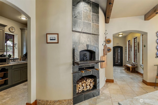 interior space with beam ceiling, sink, and light tile floors