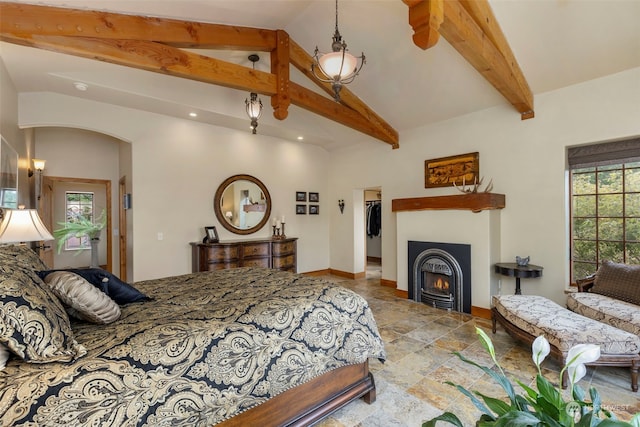 tiled bedroom with a walk in closet, lofted ceiling with beams, and multiple windows