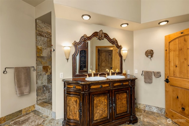 bathroom with tiled shower, double sink vanity, and tile floors