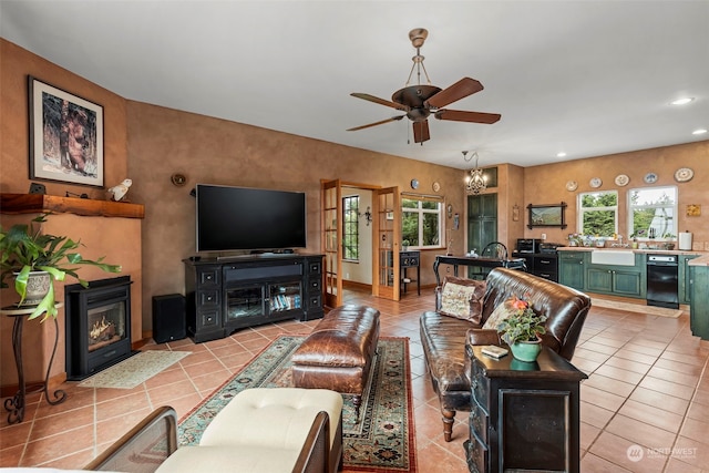 living room featuring sink, plenty of natural light, light tile floors, and ceiling fan with notable chandelier