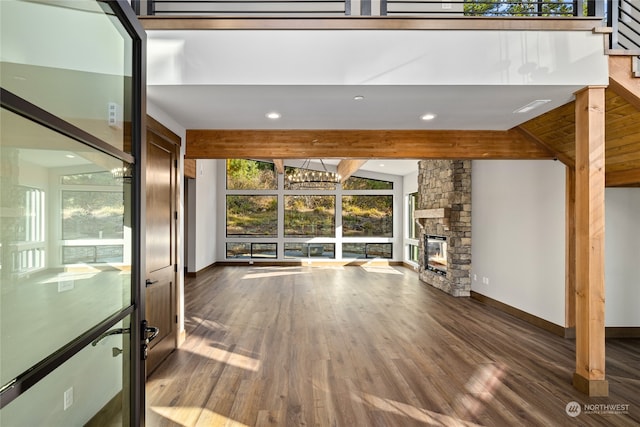 unfurnished living room with dark hardwood / wood-style flooring, a fireplace, a healthy amount of sunlight, and vaulted ceiling with beams