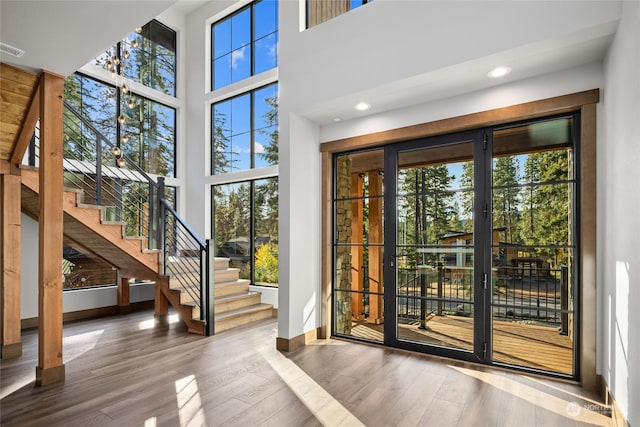 doorway featuring baseboards, wood finished floors, a towering ceiling, and stairway