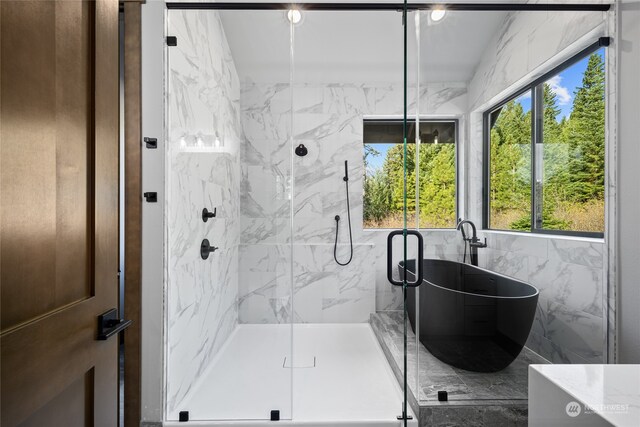 full bathroom featuring a soaking tub and a marble finish shower