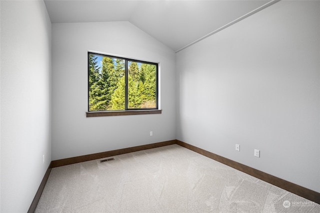 carpeted empty room with baseboards, visible vents, and vaulted ceiling