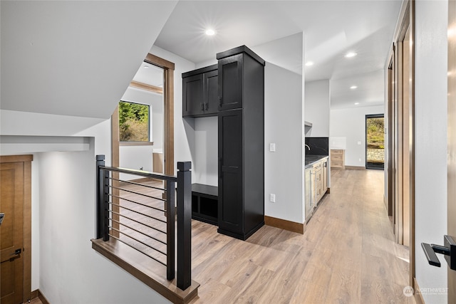 interior space with light wood-type flooring, baseboards, an upstairs landing, and recessed lighting