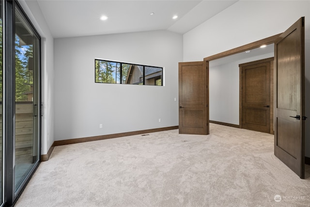 unfurnished bedroom featuring lofted ceiling, light carpet, and baseboards