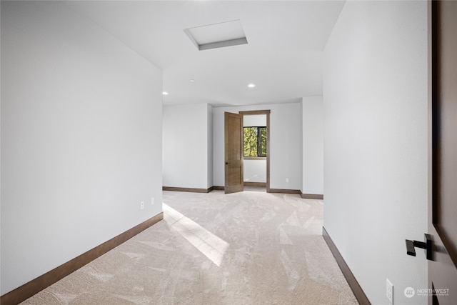 spare room with light carpet, recessed lighting, attic access, and baseboards