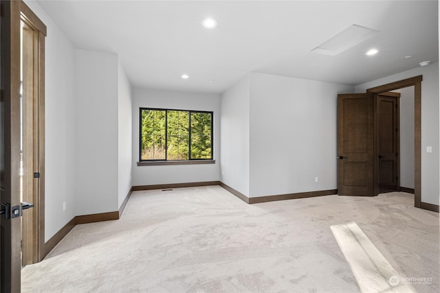 unfurnished room with recessed lighting, light carpet, attic access, and baseboards
