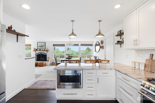 kitchen with dark hardwood / wood-style flooring, a fireplace, tasteful backsplash, white cabinets, and appliances with stainless steel finishes