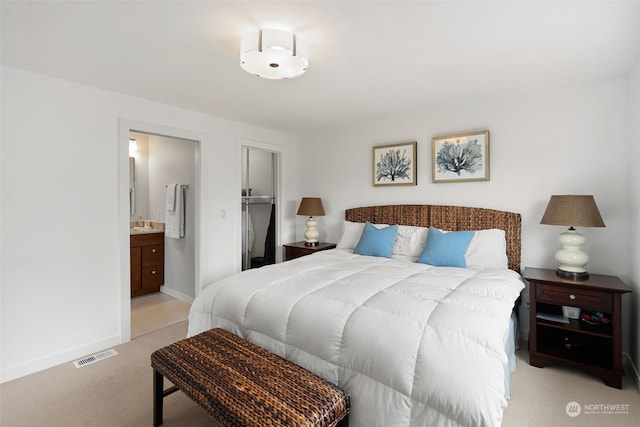 bedroom featuring light carpet, a spacious closet, sink, a closet, and ensuite bathroom