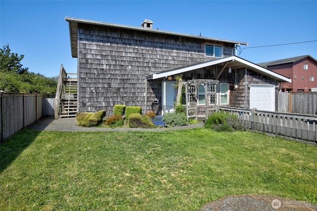 back of house with a fenced backyard, stairs, a lawn, and a garage