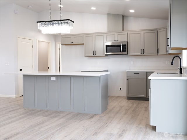 kitchen featuring a center island, sink, light hardwood / wood-style floors, and high vaulted ceiling