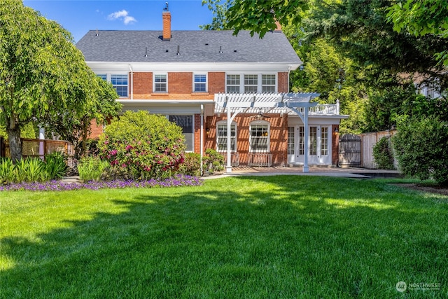 rear view of property featuring a pergola and a yard