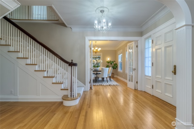 entryway featuring an inviting chandelier, crown molding, and light hardwood / wood-style flooring