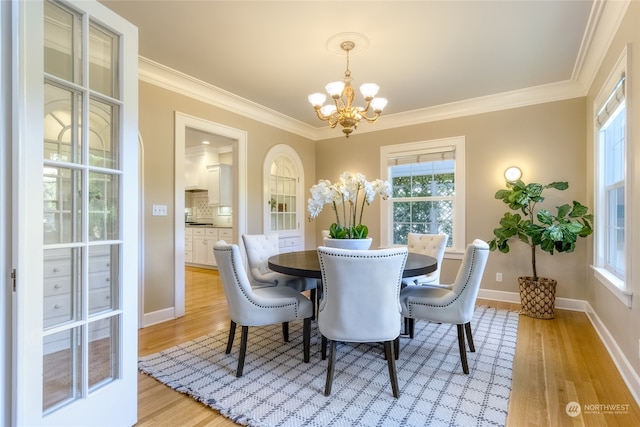 dining area featuring light hardwood / wood-style flooring, ornamental molding, and an inviting chandelier