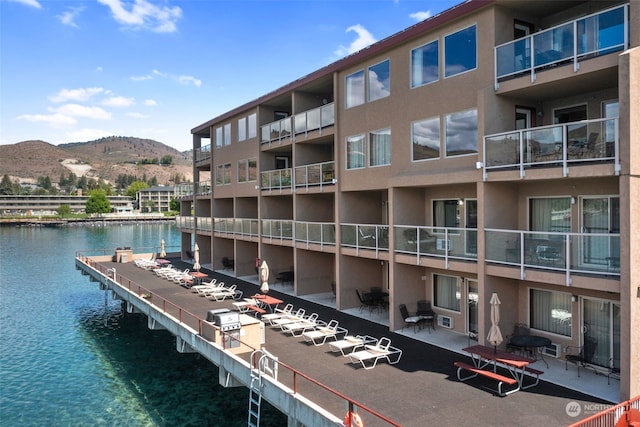 view of dock with a balcony and a water and mountain view