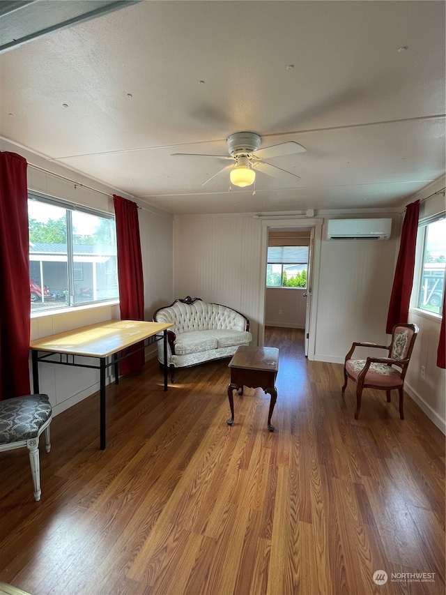 living area with hardwood / wood-style floors, a wall mounted AC, a healthy amount of sunlight, and ceiling fan