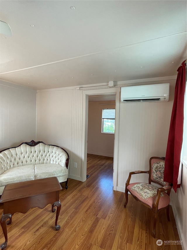 sitting room with hardwood / wood-style floors, wooden walls, and a wall mounted AC