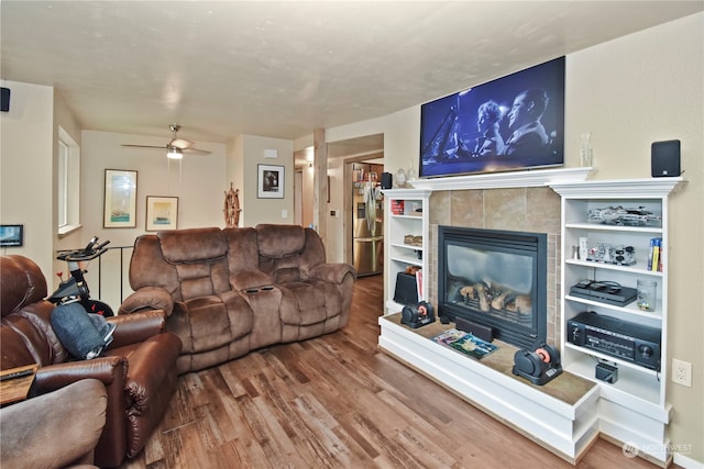 living room featuring a tiled fireplace, ceiling fan, and hardwood / wood-style flooring