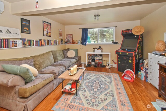 living room with a wall mounted air conditioner and light hardwood / wood-style flooring