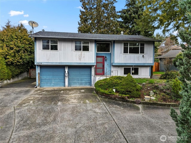 bi-level home with a garage, driveway, and fence