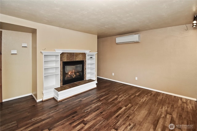 unfurnished living room featuring a tile fireplace, baseboards, dark wood-type flooring, and a wall mounted AC