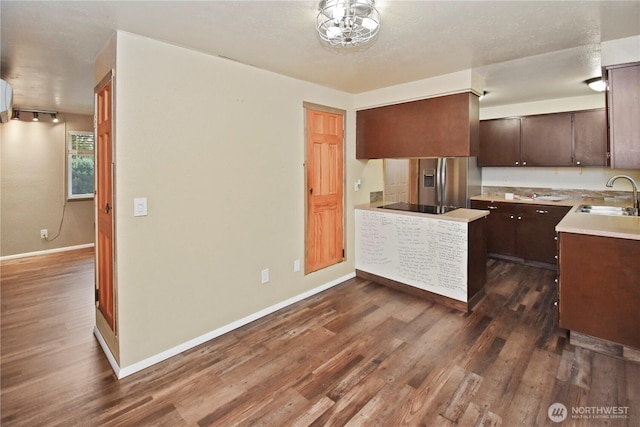 kitchen featuring dark wood-style floors, light countertops, a sink, dark brown cabinets, and stainless steel fridge with ice dispenser