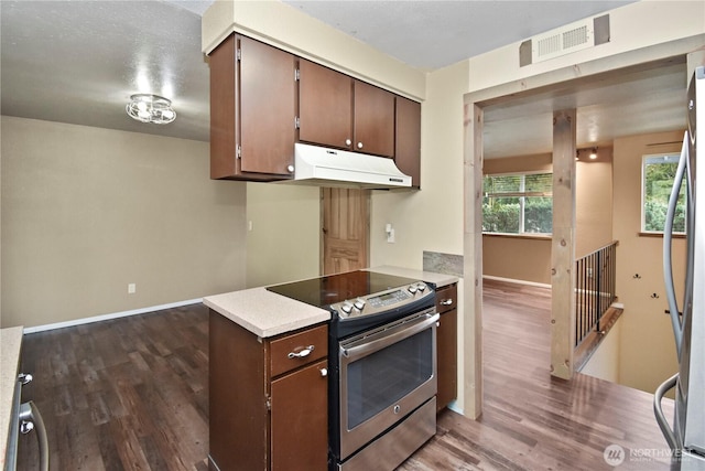 kitchen with visible vents, dark wood-style flooring, stainless steel appliances, light countertops, and under cabinet range hood