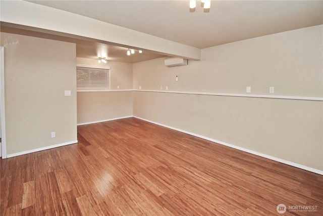 spare room with baseboards, wood finished floors, and a wall mounted AC