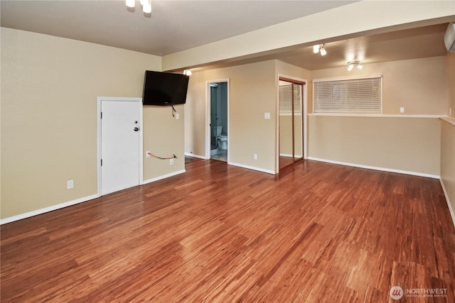 spare room with baseboards, wood finished floors, and a wall mounted AC