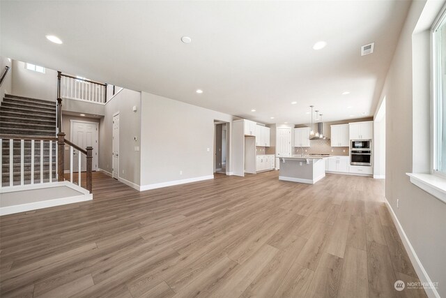 unfurnished living room featuring sink and light wood-type flooring