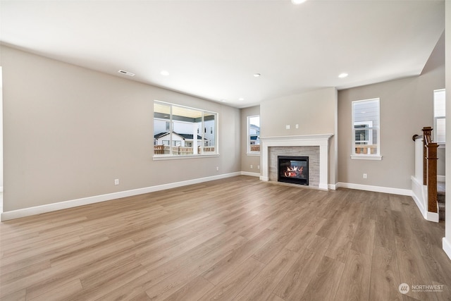 unfurnished living room featuring visible vents, a fireplace, light wood-style flooring, and baseboards