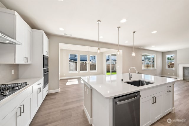 kitchen featuring stainless steel appliances, tasteful backsplash, visible vents, open floor plan, and a sink