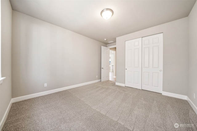 unfurnished bedroom featuring carpet floors, baseboards, and a closet